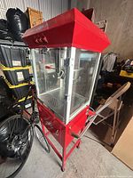 Full view of red popcorn machine on cart with glass enclosure and wheels