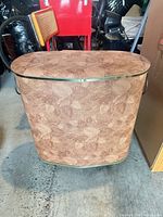 Front view of brown leaf-pattern vinyl laundry basket with gold-tone trim and side handles