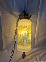 Lamp illuminated showing painted scene and chain