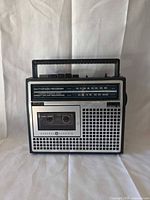 Front view showing tuning scale, cassette deck, speaker grille and handle