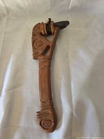 Front view of carved wooden axe with stone blade