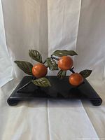 Full view of metal fruit and leaf sculpture on black base