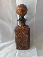 Front view of leather-covered glass decanter with spherical stopper showing crest design and gold "C.A.C."