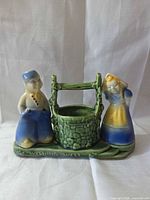Front view of ceramic wishing well planter with boy and girl figures