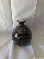 Front view of dark brown glazed ceramic liquor bottle showing gold lettering
