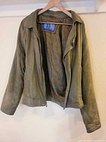 Full view of olive green leather jacket front open on hanger