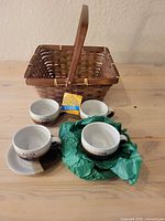 All items: four cups, four saucers, wicker basket on table