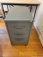 Front view showing three drawers, lock and casters