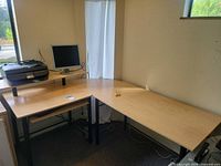 Overall view of L-shaped desk with monitor, printer, keyboard and cables