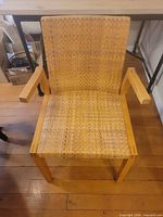 Front view of armchair showing cane seat/back and wooden arms