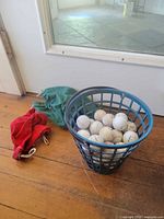 Basket with golf balls and two bags on floor