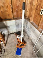 Full view of Allied orange hydraulic floor jack with handle and manual