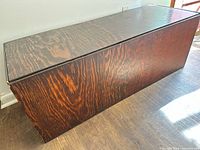 Closed rectangular dark brown plywood toy chest trunk on floor