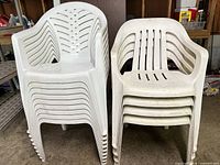 Front view of two stacks of white plastic patio chairs