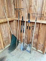 All seven garden tools leaning/hanging inside wooden shed