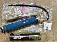 Grease gun, hose, and grease cartridge laid out