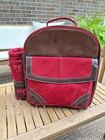 Front view of red/brown picnic backpack with front pocket and detachable bottle holder