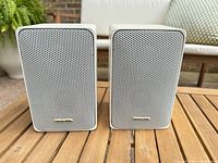 Front view of both white Minimus-7 speakers showing grilles and badges