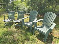Front view of four green Adirondack chairs on lawn