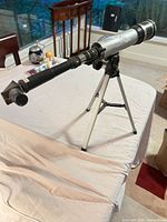 Side view of refractor telescope mounted on tripod on table