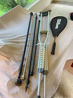 Overall lot showing crutches, curtain rods, Wilson racquet with cover