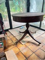Full view of round mahogany pedestal table showing overall design and brass-capped feet