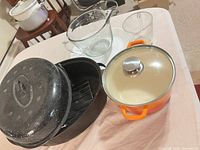 Group shot of Dutch oven, enamel roaster with rack, glass measures, pitcher, white plate