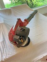 Overall view of Homelite red handheld gas blower with tube attached