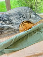 Fan fully opened showing painted landscape and bamboo ribs