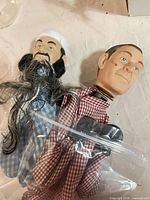 Two ventriloquist dummy heads with plaid cloth torsos and plastic hands