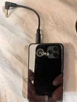Black power bank with reflection and 3.5 mm AUX cable visible