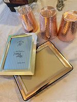 Group view of four wrapped copper cups and three silver-plated frames