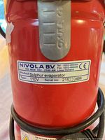 Close-up of manufacturer label on red cylinder showing brand, product type, voltage