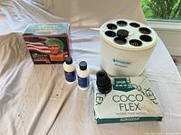Group view of hydroponic planter, Coco Flex box, two Bluelab solution bottles and boxed Trump chia pet