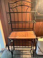 Front view of baker's rack showing shelves, wood top, wine rack