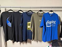 Front view of all five T-shirts on hanging rail