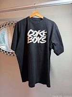 Front view of black T-shirt showing "Coke Boys" graphic
