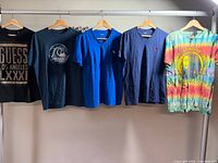 Five men’s t-shirts hanging on rod