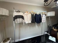 Front view of rack showing several long-sleeve tops, sweaters and sleeveless tanks