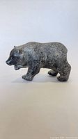side view of metal bear figurine showing raised front paw and painted finish