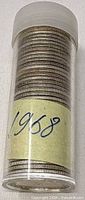 Plastic tube filled with stacked quarters, handwritten 1968 label visible