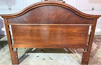 Front view of arched brown wood-veneer headboard