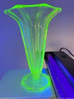 Vase glowing bright green under UV light showing fluted shape and rim