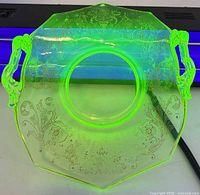 Dish glowing green under UV light showing uranium content and handle form