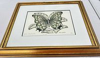 Framed lithograph angled view showing butterfly artwork and gold frame