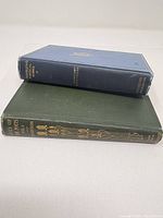 Blue and green hardcover books stacked showing spines.
