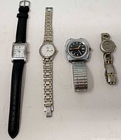 Four wristwatches lined side by side on white surface
