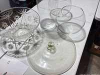 Overview showing cut glass bowl, two fishbowl vases, large glass lid