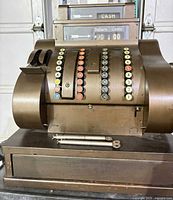 Front view of cash register showing keys, display, wood base, crank and keys laid on drawer