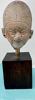 Front view of terracotta tribal head on wood stand